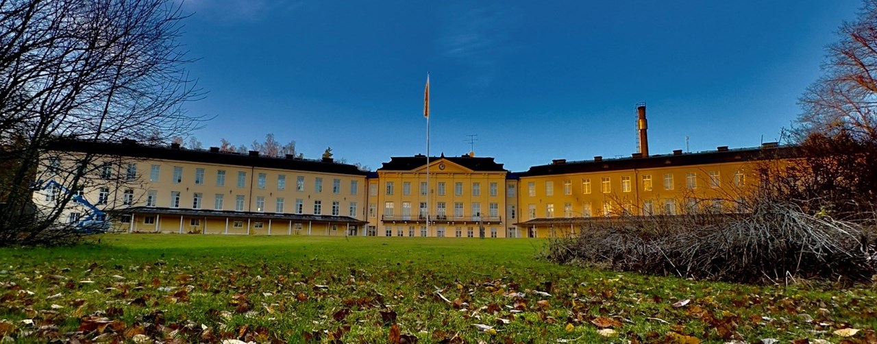 Höstbild på SiS LVM-hem Hessleby med blå himmel och höstlöv på marken.